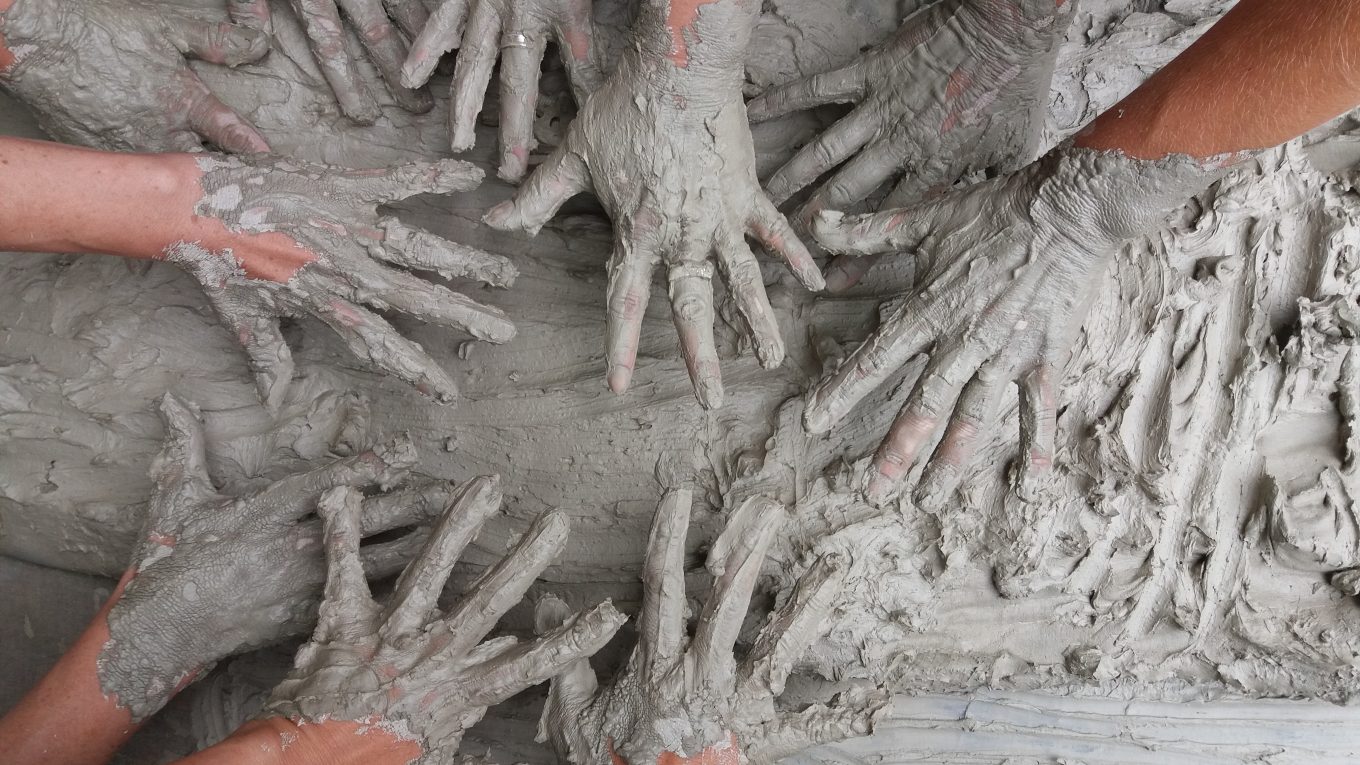 multiple hands covered in mud