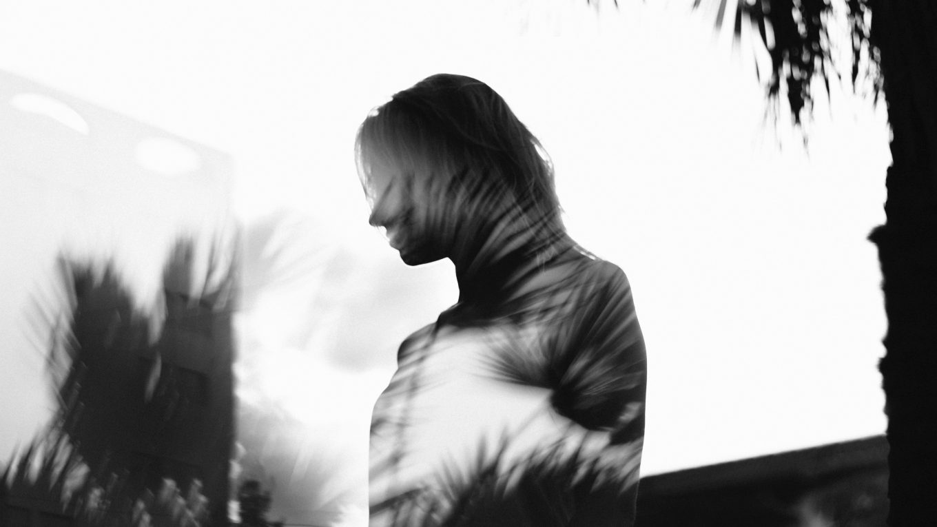 Silhouette of a woman in the reflection of glass with trees and plants around her