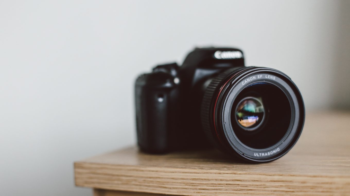 Canon camera on the corner of a wooden table